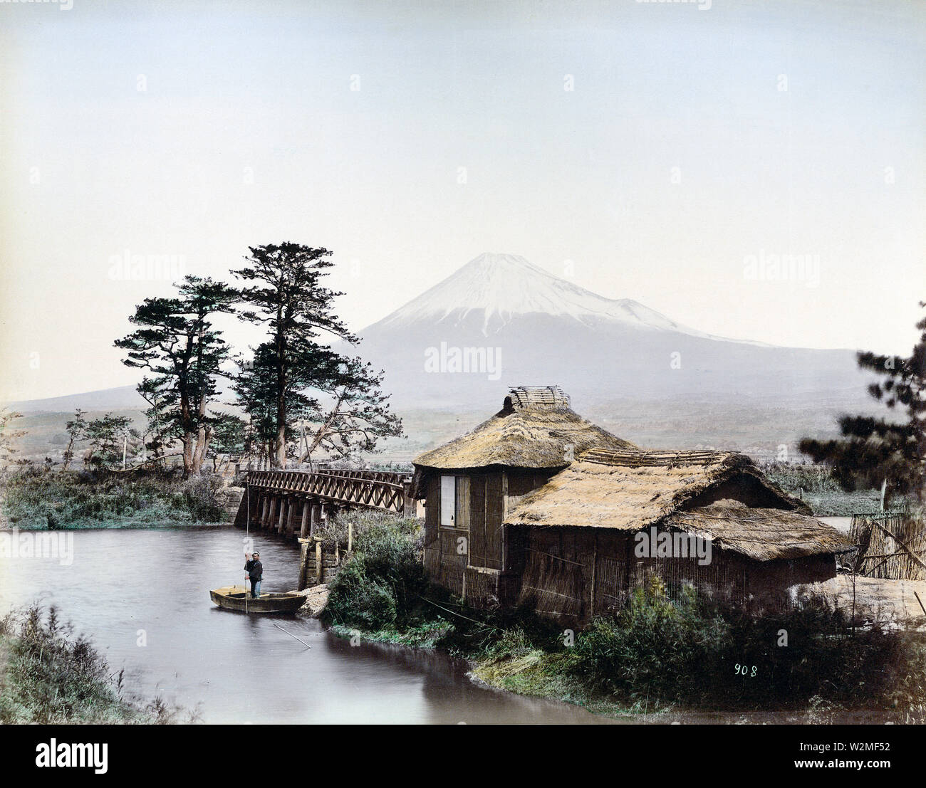 [1880s Japan - Kawaibashi Brücke auf der Tokaido] - Kawaibashi Brücke überspannt den Fluss in der Nähe von Taganoura Numakawa der Tokaido. Im Vordergrund ist ein Gebäude mit Strohdach, daneben ist ein kleines Wharf, wo ein Mann in ein kleines Holzboot steht. Im Hintergrund Mt. Fuji gesehen werden kann. Die Numakawa fließt von Ukishima Teich in Richtung Tagonoura. Vor der Brücke während des Kanbun-Ära (1661-1673) erbaut wurde, Menschen gekreuzt dieser Standort mit der Fähre. Über die Brücke Strommasten kann gesehen werden, dass dieses Bild in den 1880er Jahren aufgenommen wurde. 19 Vintage albumen Foto Stockfoto