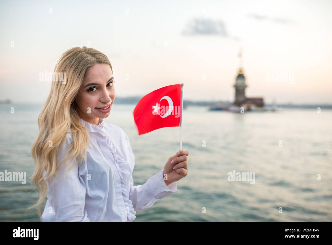 Attraktive junge schöne Mädchen wellen Türkische Flagge und genießt den Sonnenuntergang Blick auf den Bosporus und Maiden Tower in Istanbul, Türkei. Travel Concept Stockfoto