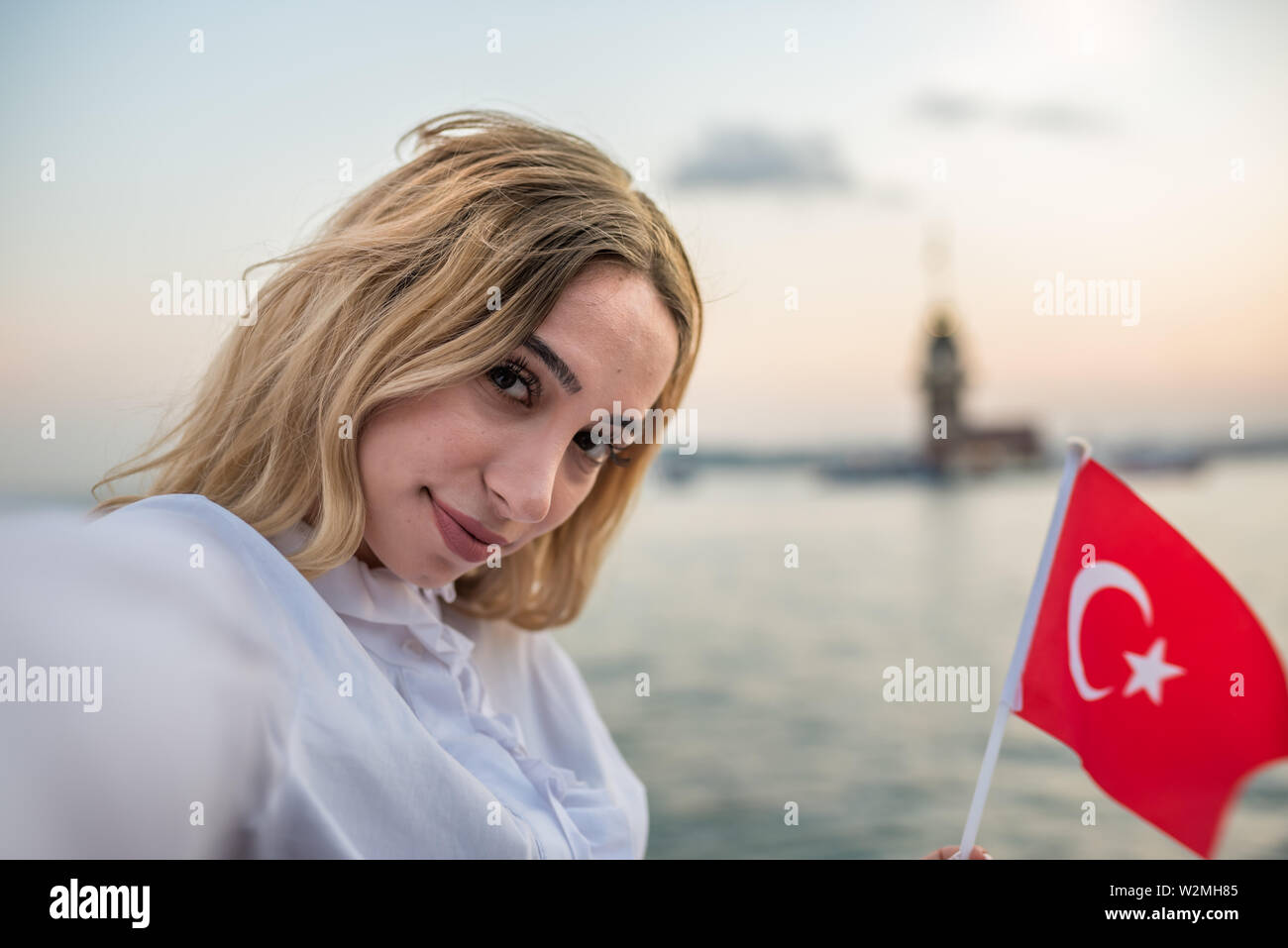 Attraktive junge Schöne nimmt selfie während winken Türkische Flagge und genießt den Sonnenuntergang Blick auf den Bosporus und Maiden Tower in Istanbul, Türkei. Reisen Conce Stockfoto