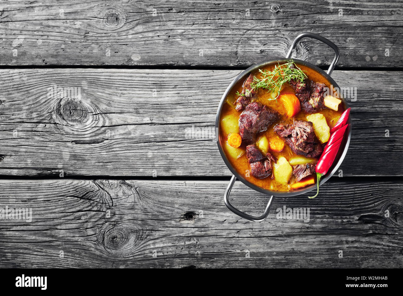 Ansicht von oben der traditionellen jamaikanischen Curry Goat - langsam gekocht Jamaikanischen gewürztem Fleisch und Gemüse würzige Curry in einem Topf auf einem rustikalen Holztisch, Anzeigen Stockfoto