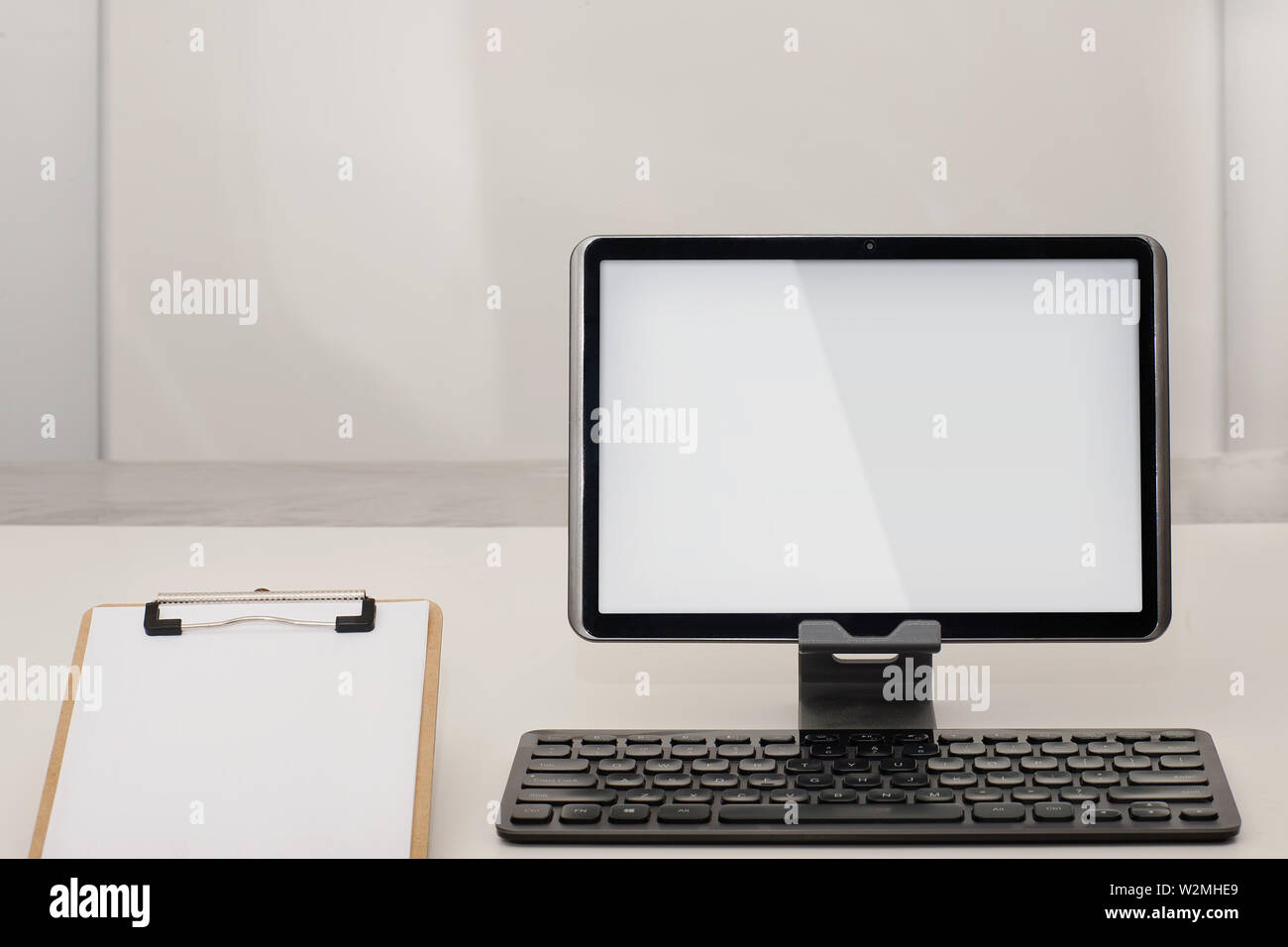 Ein 10-Zoll Tablet-PC mit Wireless Keyboard und die Zwischenablage mit Papier in einem leeren Büro Zimmer. Stockfoto