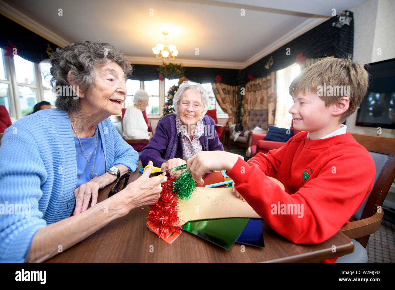 Schulkinder in der Bristol besuchen Pflegeeinrichtungen zu Weihnachten Dekorationen machen mit Bewohnern in einem Programm organisiert von der Nächstenliebe lebendig Tätigkeit Stockfoto