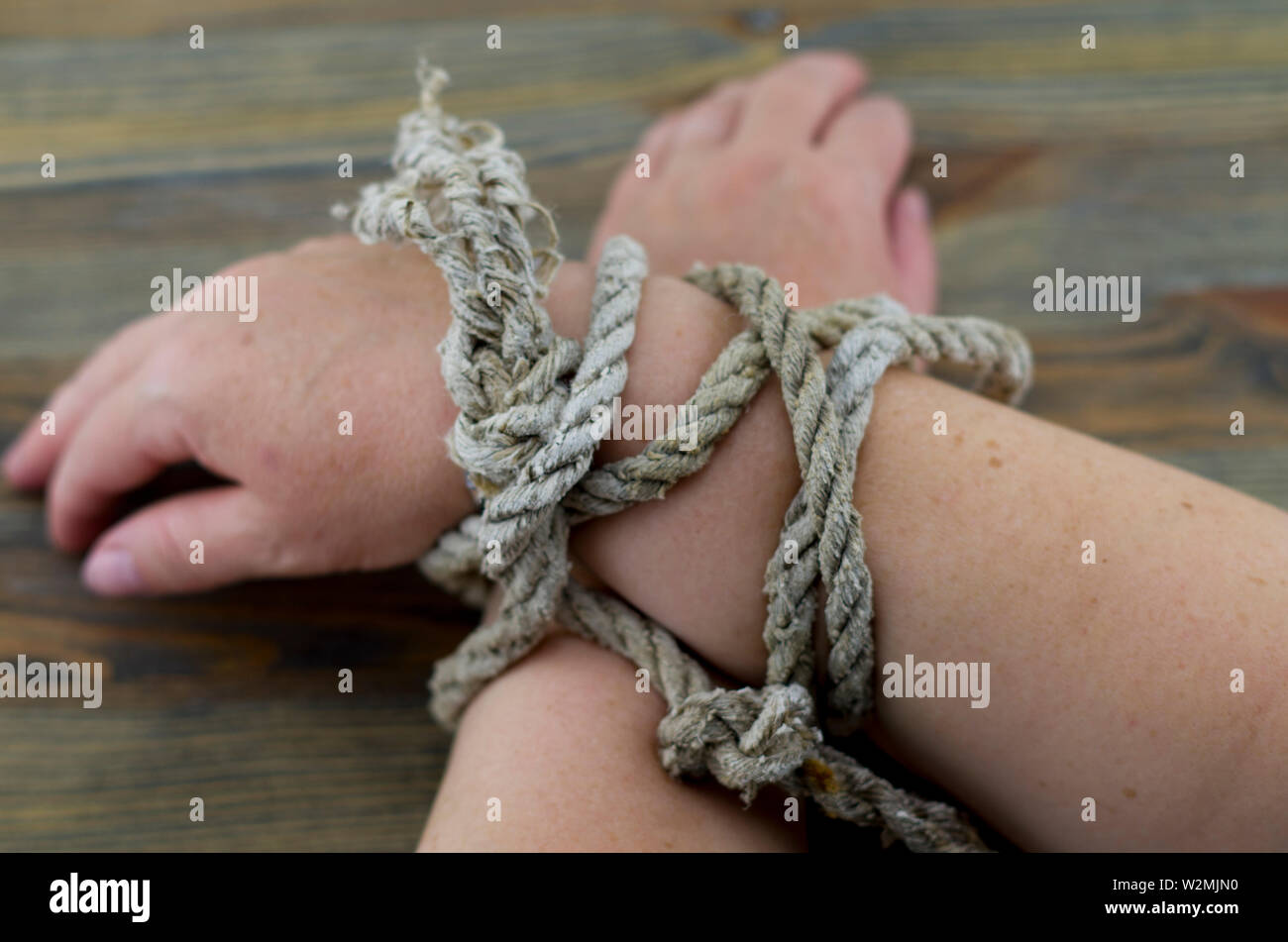 Die Frau Hände mit einem alten Seil gebunden, das Seil grau mit dem Alter ist und Entwirren an den Enden. Es ist möglich, das Bild so zu interpretieren, als Folter. Stockfoto