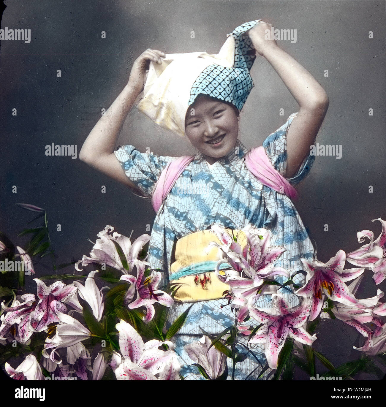 [1900s Japan - Geisha mit Lilien] - nette junge Frau in traditioneller Kleidung mit Lilien posiert, Anfang 1900. Enami Nobukuni, der Fotograf, nannte sie den "Geist der Lilien." 20. Jahrhundert vintage Glas schieben. Stockfoto