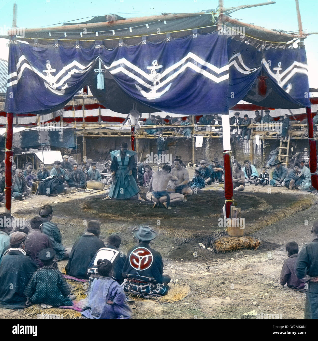 [1900s Japan - Sumo-ringer auf außerhalb der Arena, Tokio] - Sumo Ringer in einem äußeren Arena bei Eko-in Tempel (回向院) in Ryogoku, Tokio bereit, einen Kampf zu beginnen. Der Tempel wurde als Sumo Ringen Veranstaltungsort während der Edo-zeit (1603-1868) und Meiji (1868-1912) bekannt. Der erste Kampf war hier im September 1768 statt. Von Oktober 1833 (tenpo 4) bis 1909 (Meiji 42), die Zeit des "Eko-im Sumo" (回向院相撲), alle Sumo Turniere wurden im Tempel statt. 20. Jahrhundert vintage Glas schieben. Stockfoto