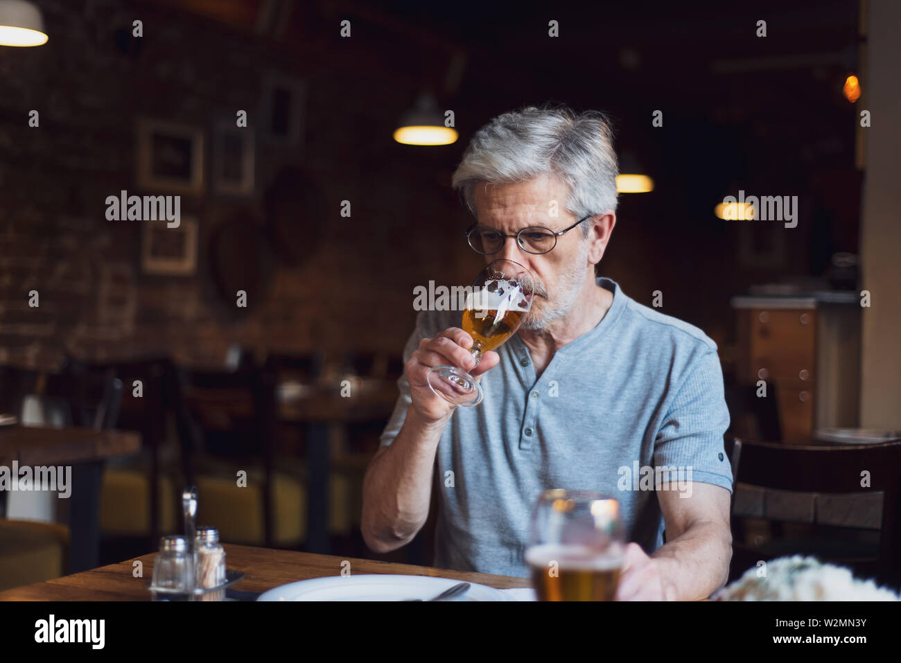 Ältere Menschen mit einem Bier in der Bar allein Stockfoto