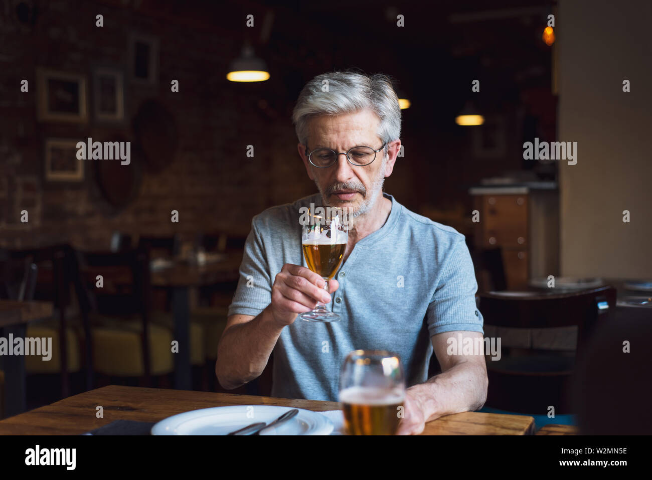 Ältere Menschen mit einem Bier in der Bar allein Stockfoto