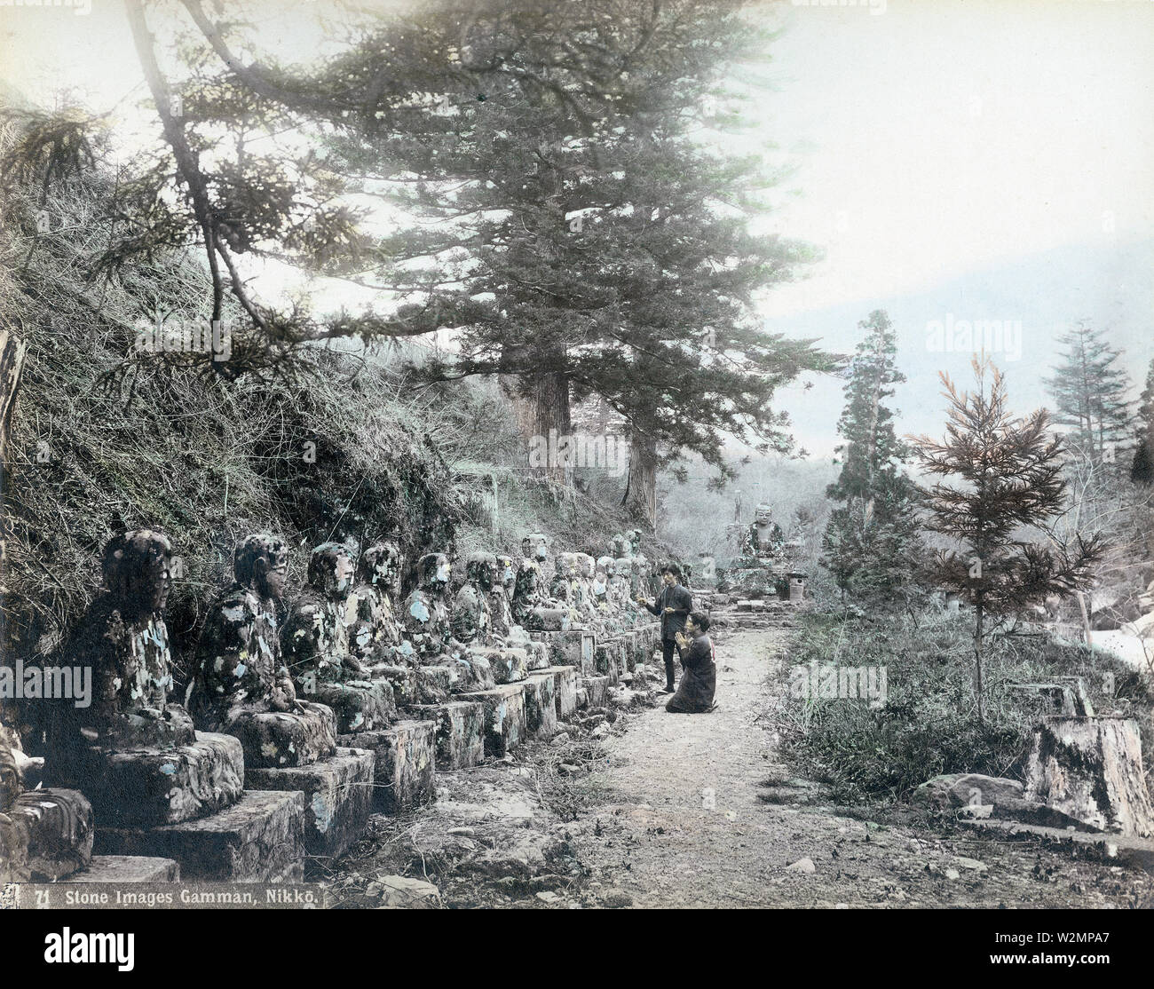 [1890s Japan - Buddhistische Statuen an Kanmangafuchi, Nikko] - ein Mensch betet vor Narabi Jizo an Kanmangafuchi, Nikko. Buddhistischen Jizo ist der Beschützer der Reisenden und Kinder. Die große Statue in der Rückseite ist Oya Jizo. Oya Jizo und viele der Narabi Jizo wurden in einer Flut 1902 zerstört (Meiji 35). 19 Vintage albumen Foto. Stockfoto
