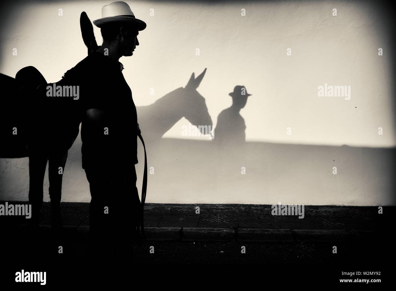 Silhouette eines Mannes in einen Strohhut mit einem Esel an der Wand reflektiert. Mahon, Balearen, Spanien, Europa. Stockfoto