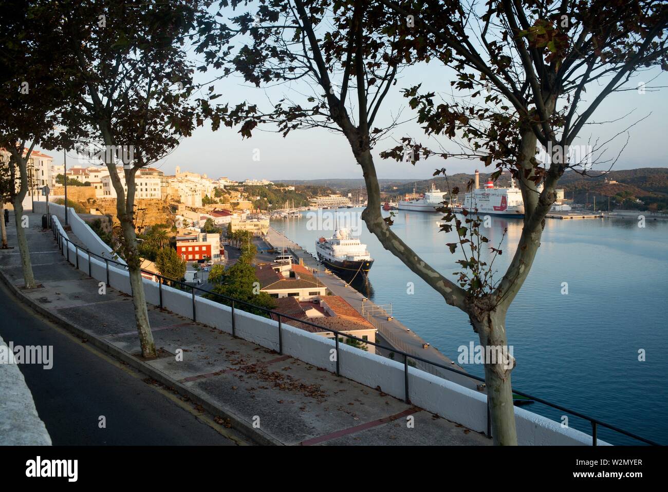 Blick auf den Hafen und die Stadt mit Bäumen im Vordergrund und ein Boot. Mahon Menorca, Balearen, Spanien, Europa. Stockfoto
