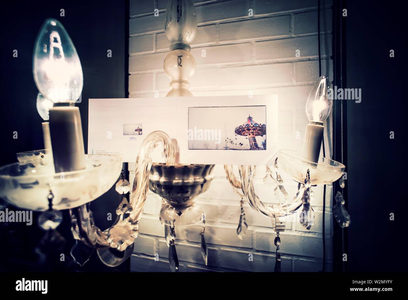 Nahaufnahme von einem Kronleuchter Lampe leuchtet mit einer Postkarte mit einem Bild von einem Karussell. Mahon, Baleares, Spanien, Europa. Stockfoto