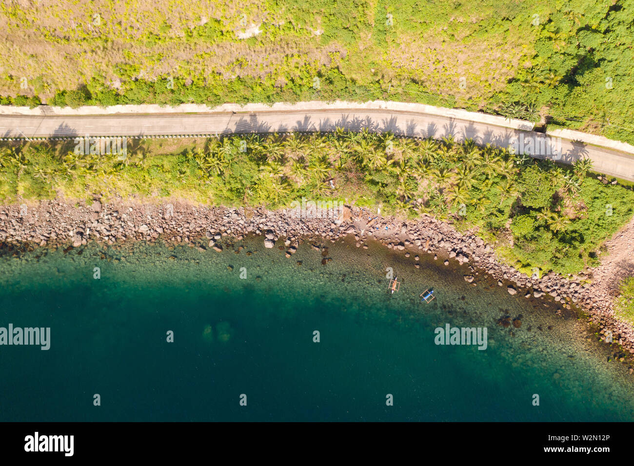 Konkrete Straße entlang der Küste, Blick von oben. Steinige Küste mit einem Blue Bay, Philippinen. Stockfoto