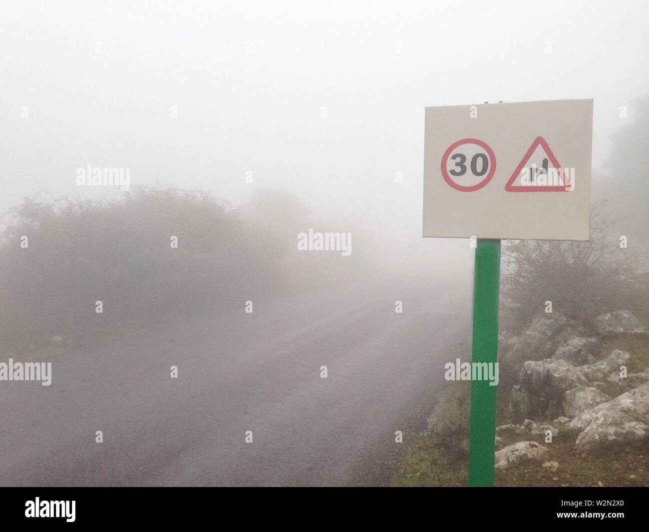 Metall Pol mit traffic signal Beratung Gefahr signal der Kurven bei Mountain Road im Nebel. Stockfoto