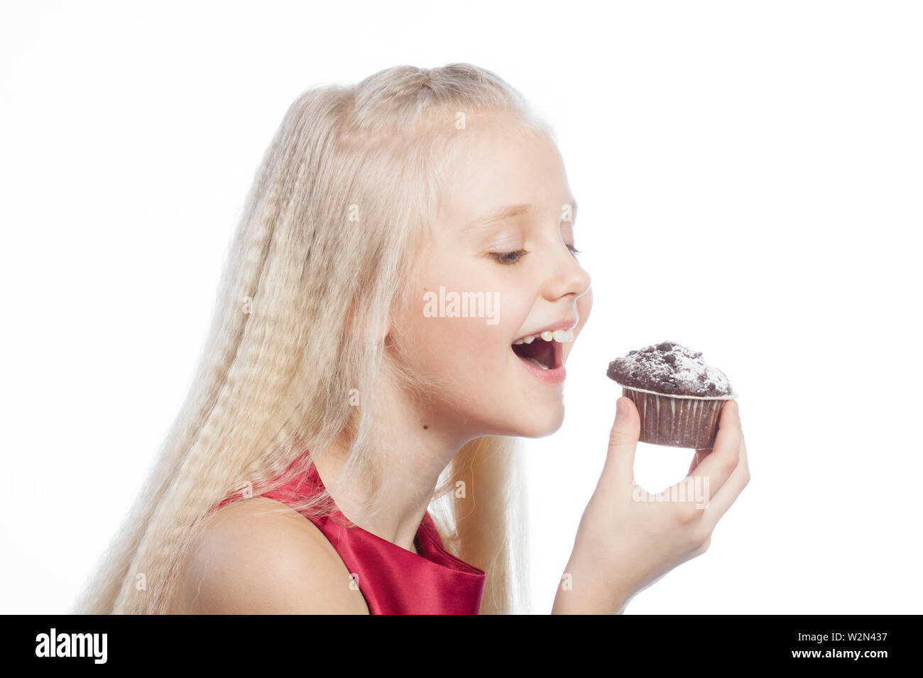 Mädchen beißen einen Schokoladenkuchen auf weißem Hintergrund. Stockfoto