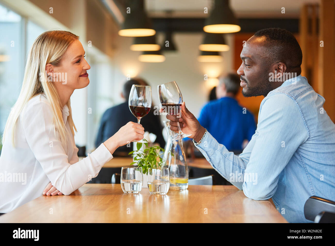 Multikulturelle junges Paar mit einem Drink, während Sie ein Rendezvous im Restaurant Stockfoto