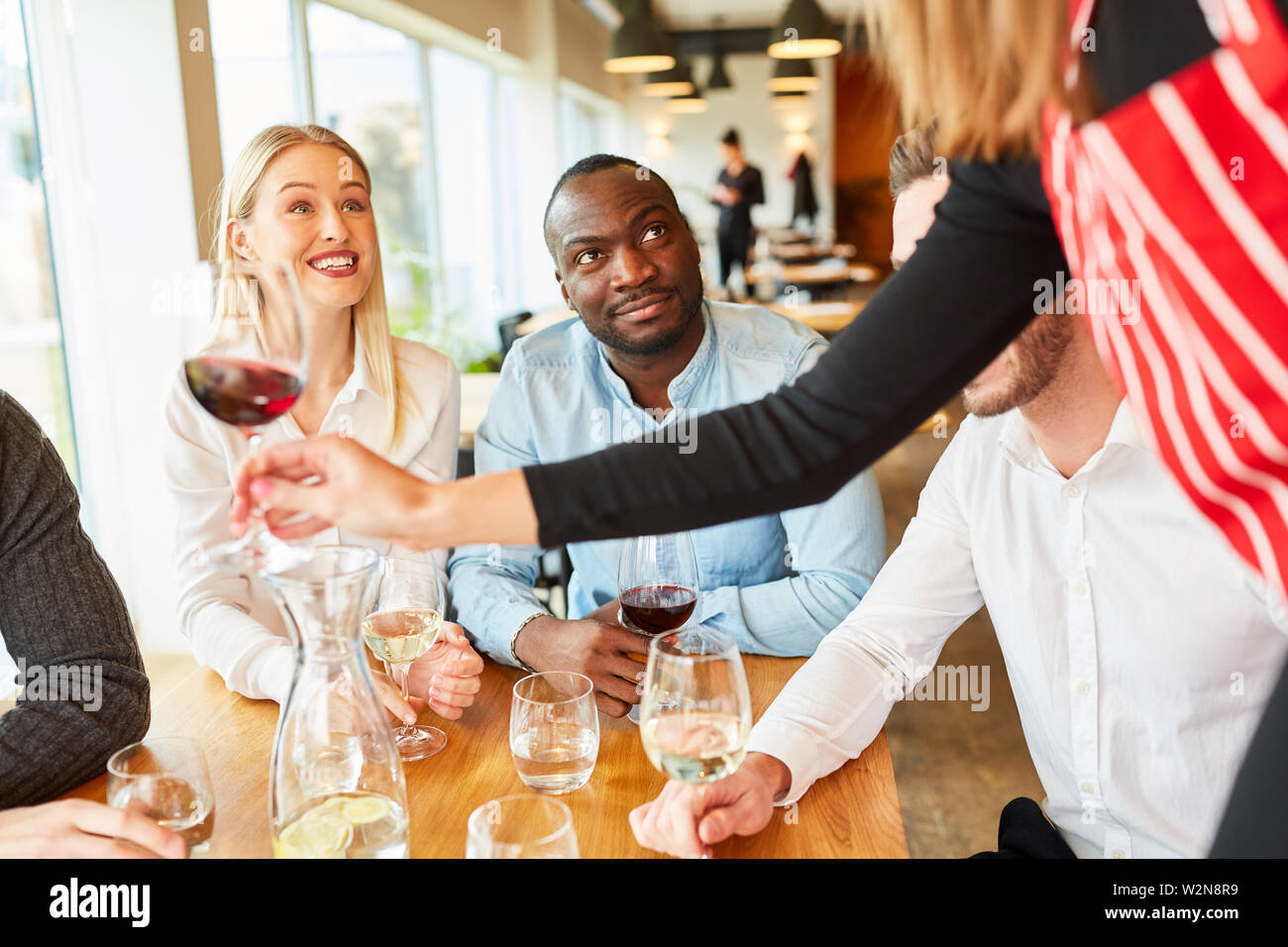 Kellnerin oder Kellnerin in der Bar oder im Restaurant serviert seinen Gästen am Tisch Wein Stockfoto