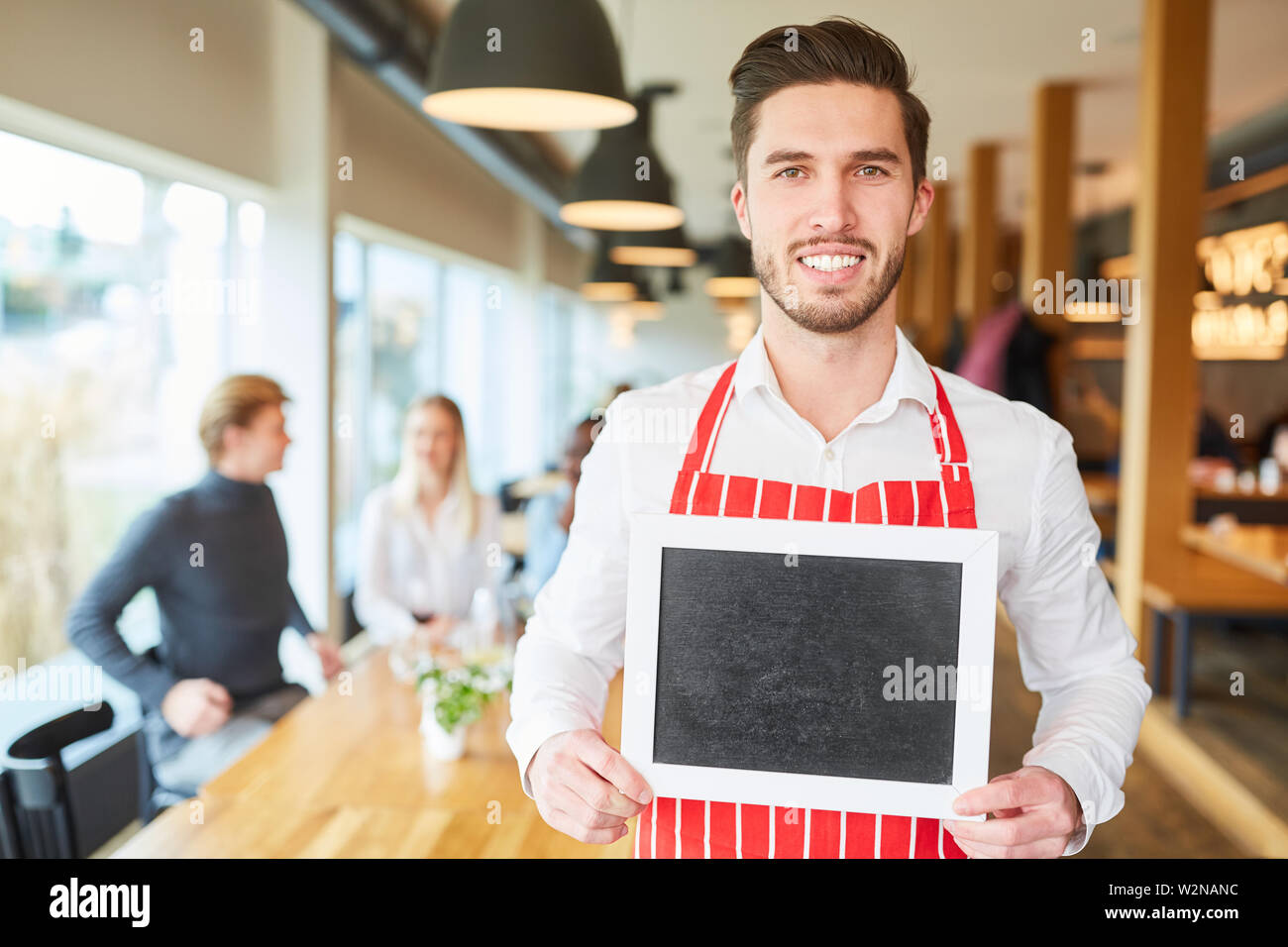 Junger Mann als Kellner oder service Arbeitnehmer mit Kreidetafel im Restaurant Stockfoto