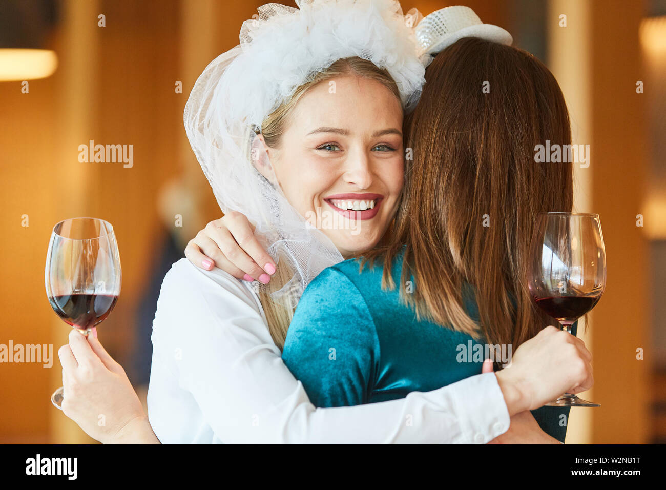 Freundin Umarmungen glückliche Braut mit Bridal Veil auf einer Party im Restaurant Stockfoto