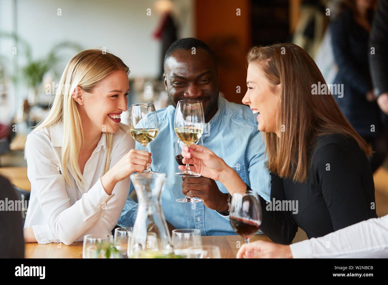 Freunde im Bistro oder Restaurant Lachen glücklich während der Verkostung mit Glas Wein Stockfoto