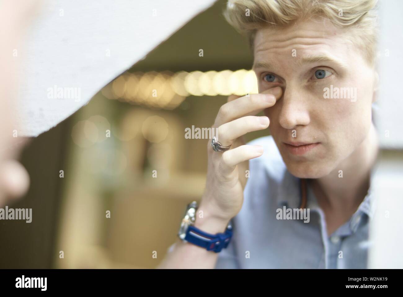 Junge Mann seine Erscheinung im Spiegel überprüfen, Augenringe  Stockfotografie - Alamy