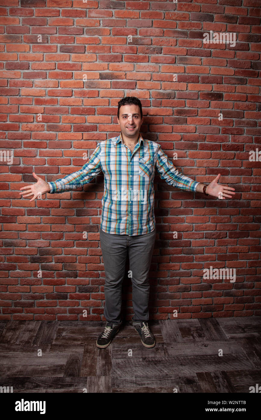 Männliche portrait Italienisch, guten und positiven Emotionen vor dem Hintergrund der Brandwand in der Art Loft. In klechatoy Shirt, Jeans und Turnschuhe, städtische Kleidung. Stockfoto
