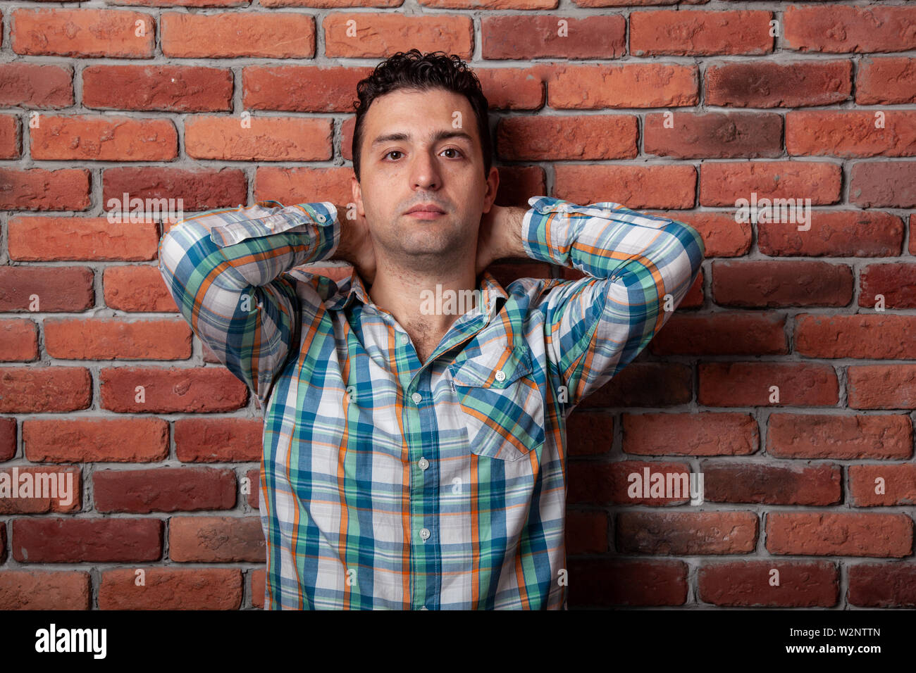 Männliche portrait Italienisch, guten und positiven Emotionen vor dem Hintergrund der Brandwand in der Art Loft. In klechatoy Shirt, Jeans und Turnschuhe, städtische Kleidung. Stockfoto