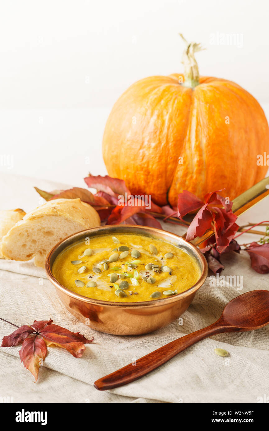 Kürbis Suppe in einer Kupfer Topf mit Samen serviert. Herbst Mittagessen Konzept mit kopieren. Stockfoto