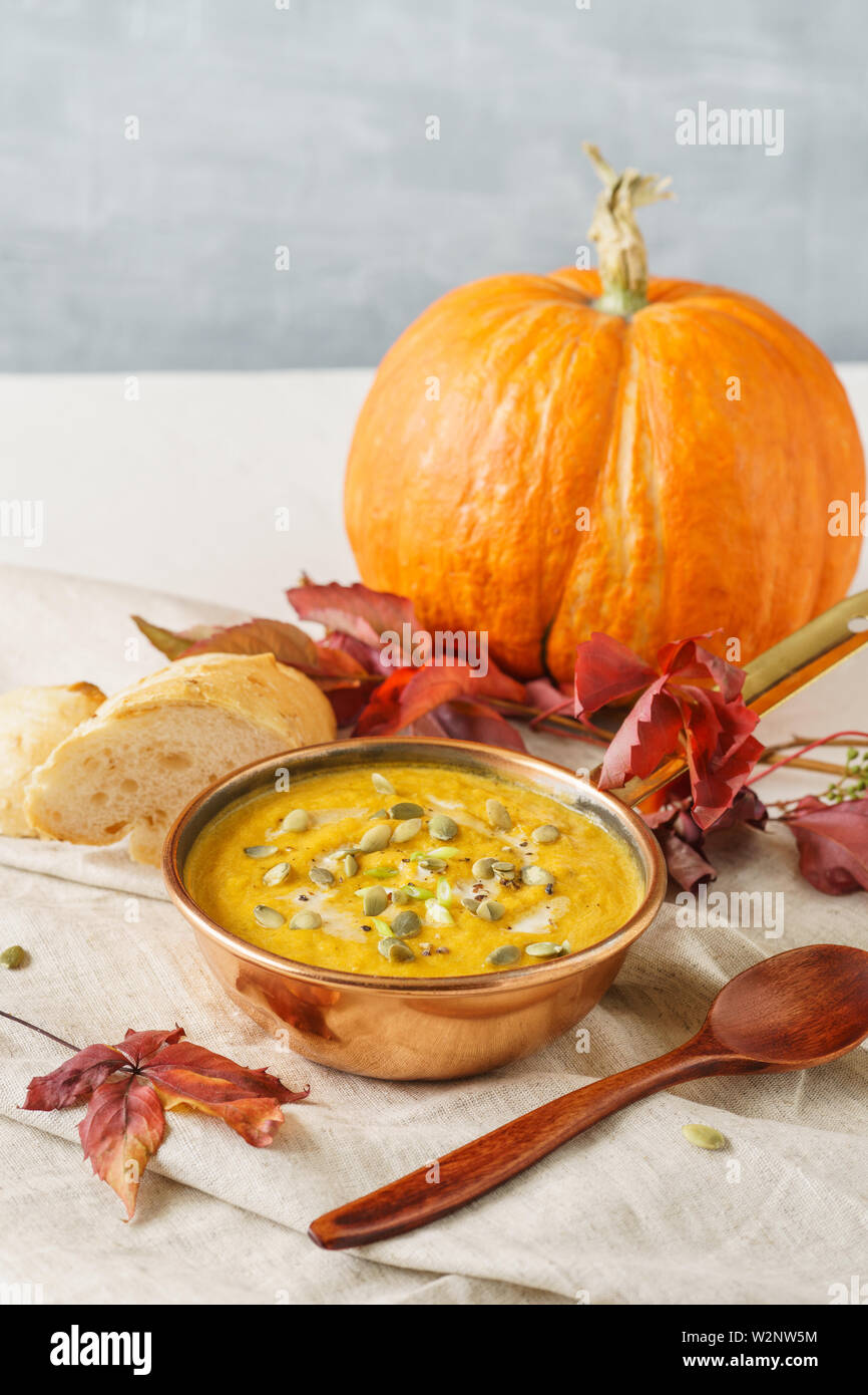 Kürbis Suppe in einer Kupfer Topf mit Samen serviert. Herbst Mittagessen Hintergrund mit Copyspace Stockfoto