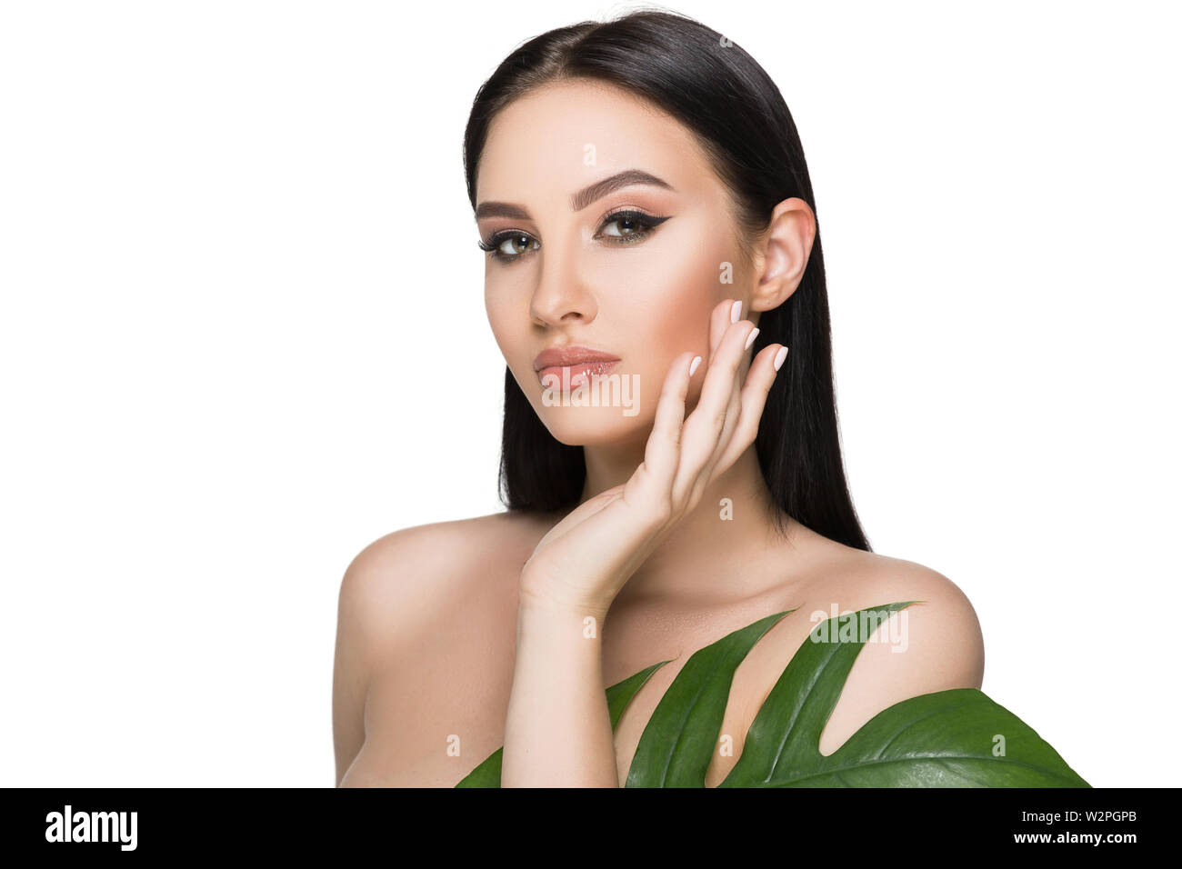 Gegerbt frau gesicht mit perfekten Make-up und gesunde Haut mit tropischen Blatt isoliert auf Weiss. Kosmetik und Gesichtspflege Stockfoto