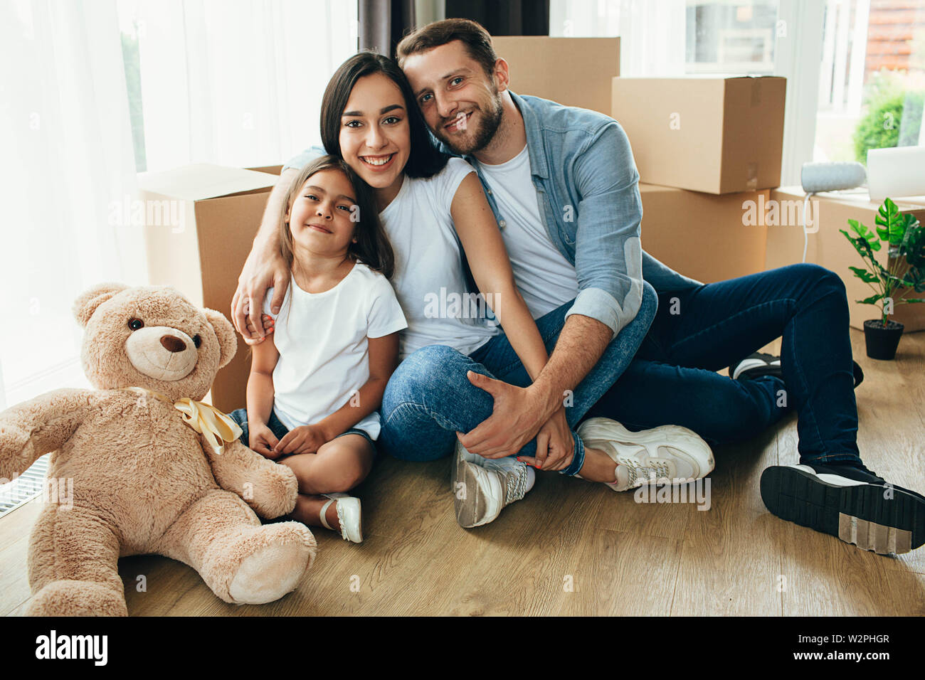 Happy Family umarmen sitzen auf dem Boden in ihr neues Haus. Es ist wunderbar, Umzug in eine neue Wohnung Stockfoto