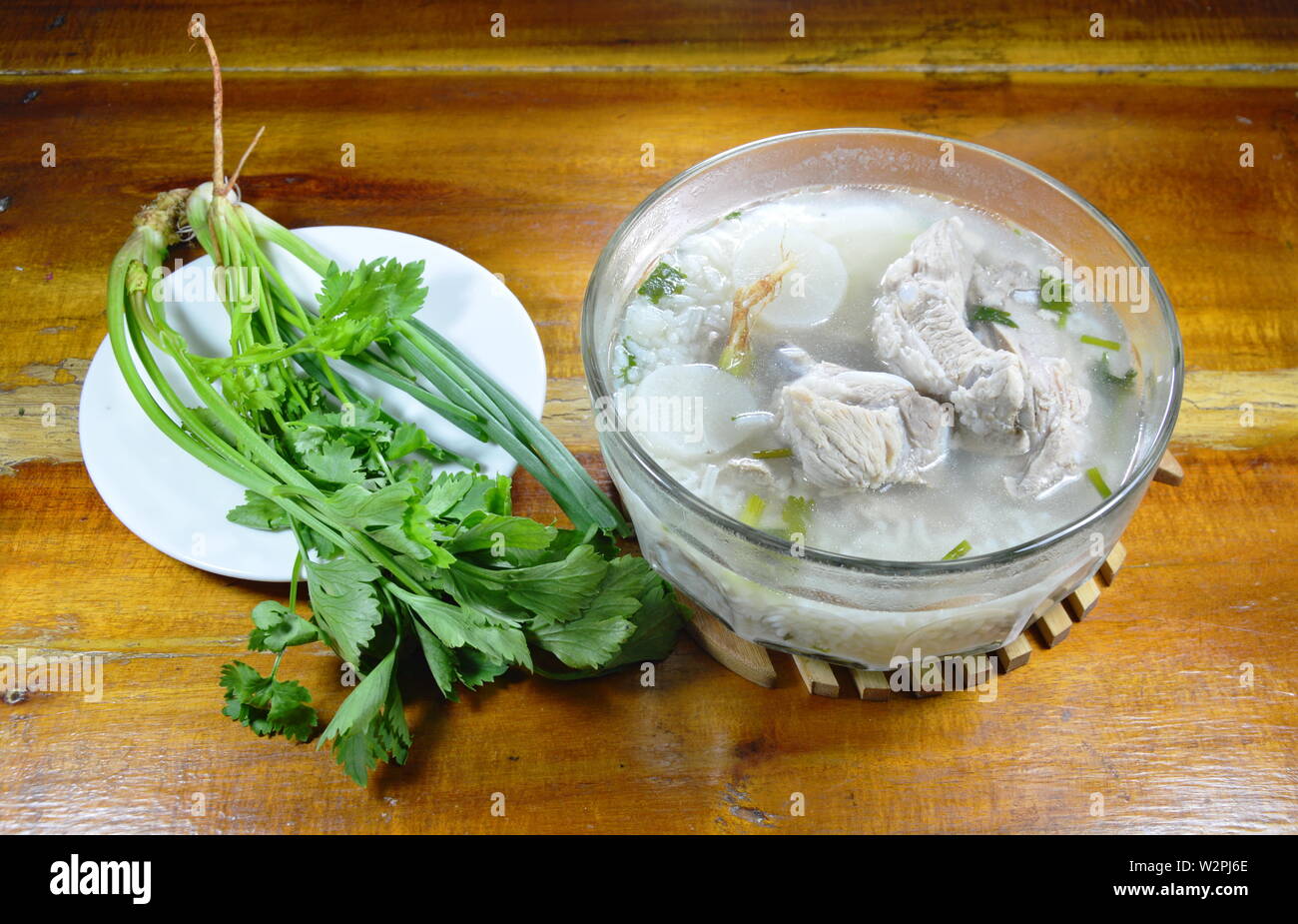 Reisbrei mit Schweinefleisch Knochen heiße Suppe und frisches Gemüse Stockfoto
