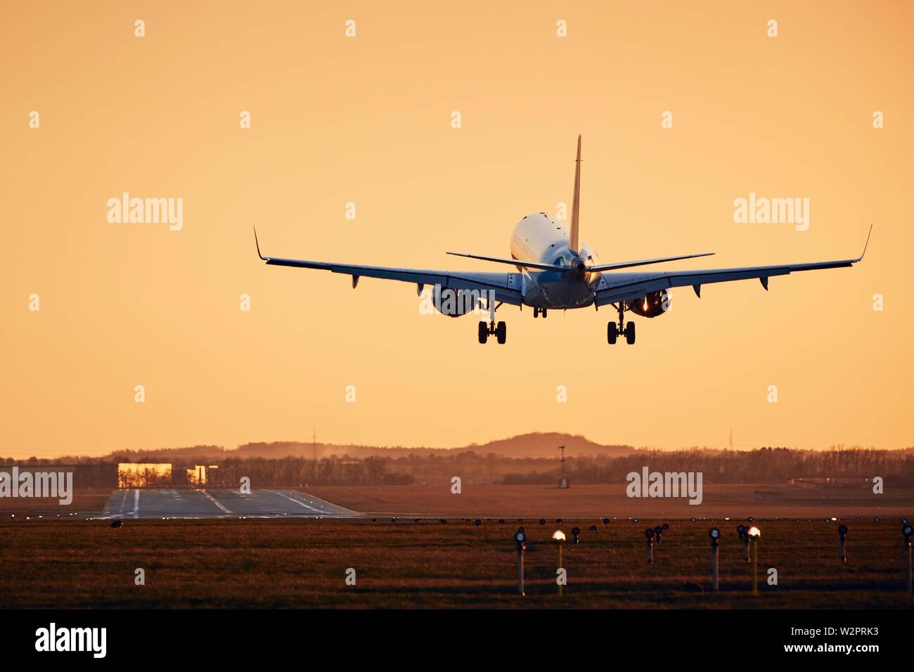 Flugzeug Landung auf der Landebahn. Verkehr am Flughafen an den goldenen Sonnenuntergang. Stockfoto