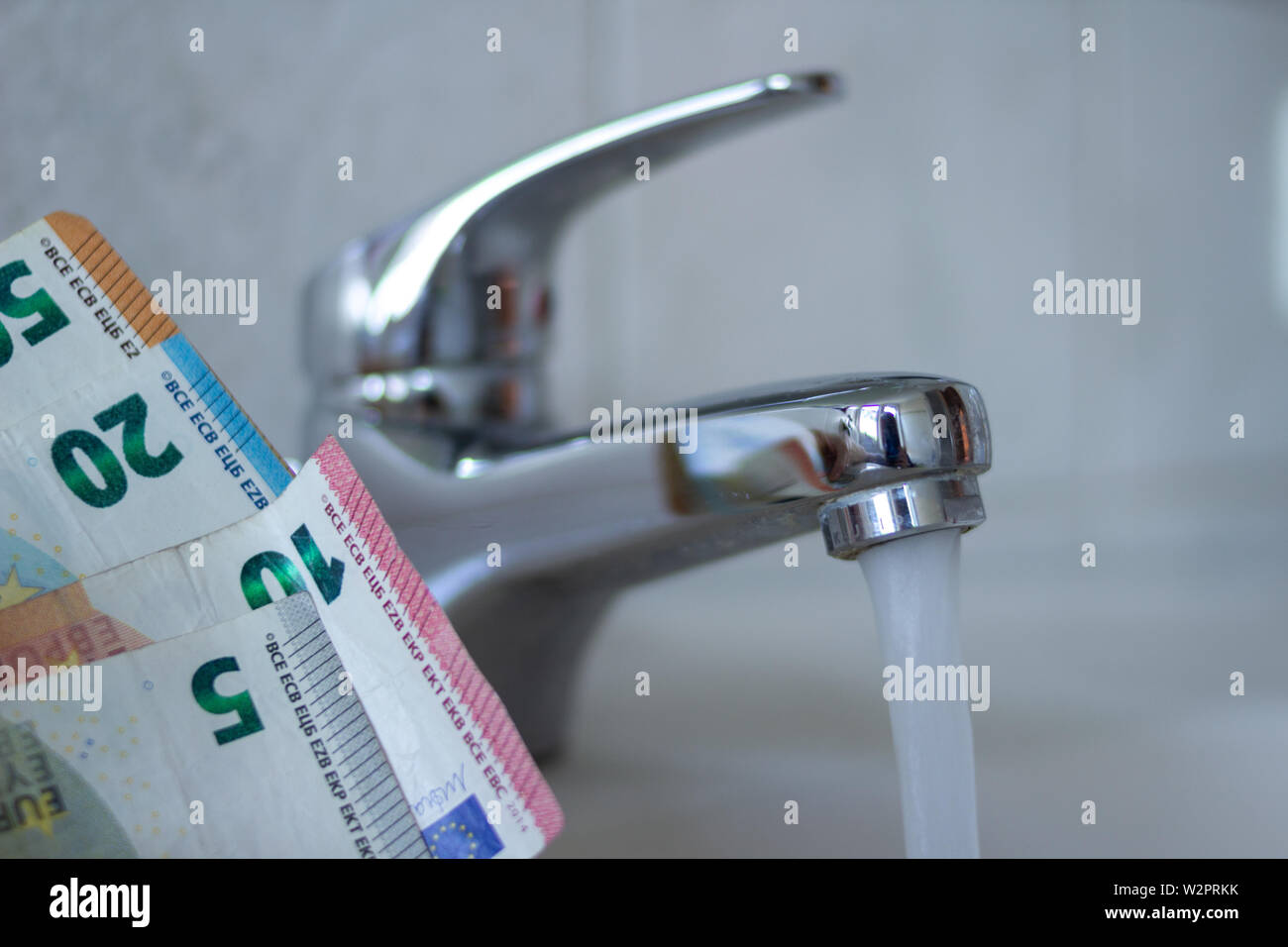 Close up Chrom Waschbecken mit Euro-Banknoten. Konzept für die Erhöhung der Wasserpreise und Haushalt Budgetplanung. Steigender Verbrauch Stockfoto
