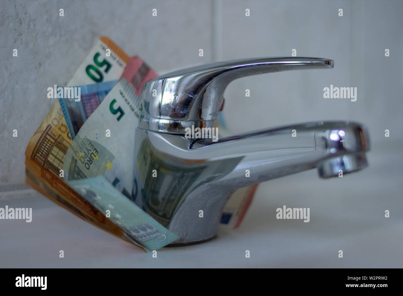 Close up Chrom Waschbecken mit Euro-Banknoten. Konzept für die Erhöhung der Wasserpreise und Haushalt Budgetplanung. Steigender Verbrauch Stockfoto