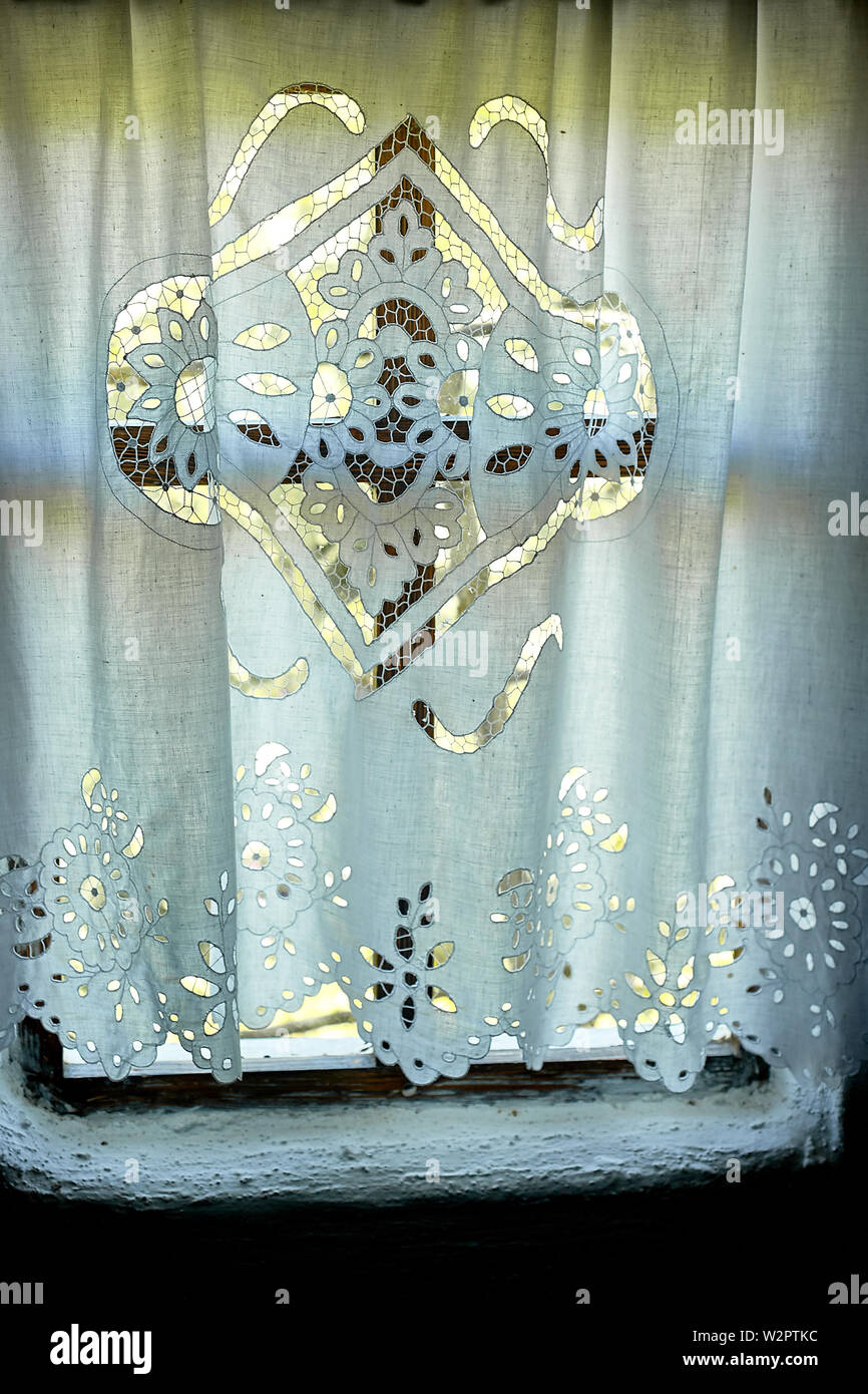 Ein Fenster in einer weiß getünchten Hütte mit einem Holzrahmen, ein Lacy Leinen gestärkten Vorhang.das Innere des Hauses. Die Ukraine, die Kosaken Stockfoto