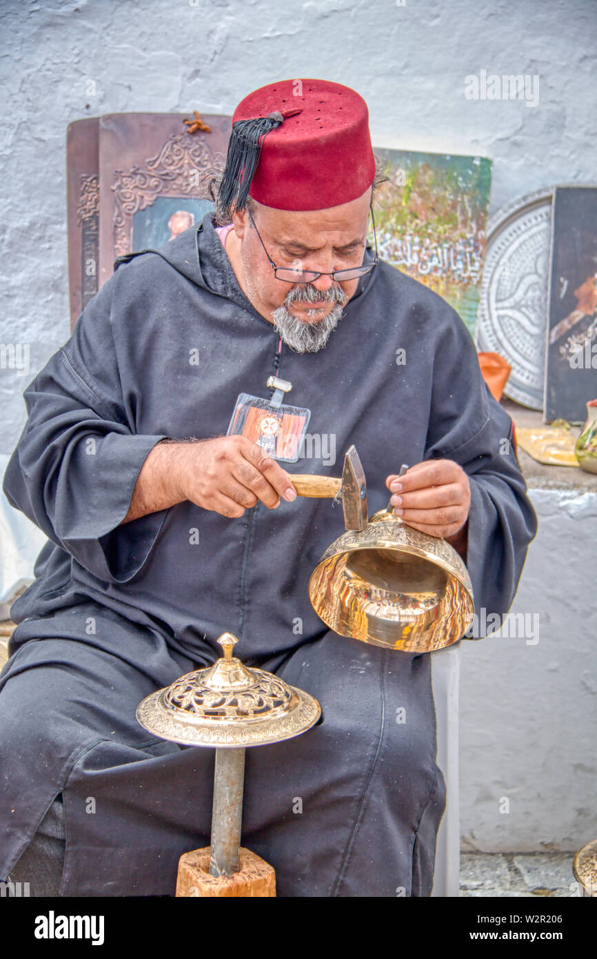 Mertola, Portugal - Mai 18, 2019: marokkanische Handwerker Carving schönen Gegenstände aus Metall in den Straßen von Mértola, wo die Islamische Festival statt Eve Stockfoto