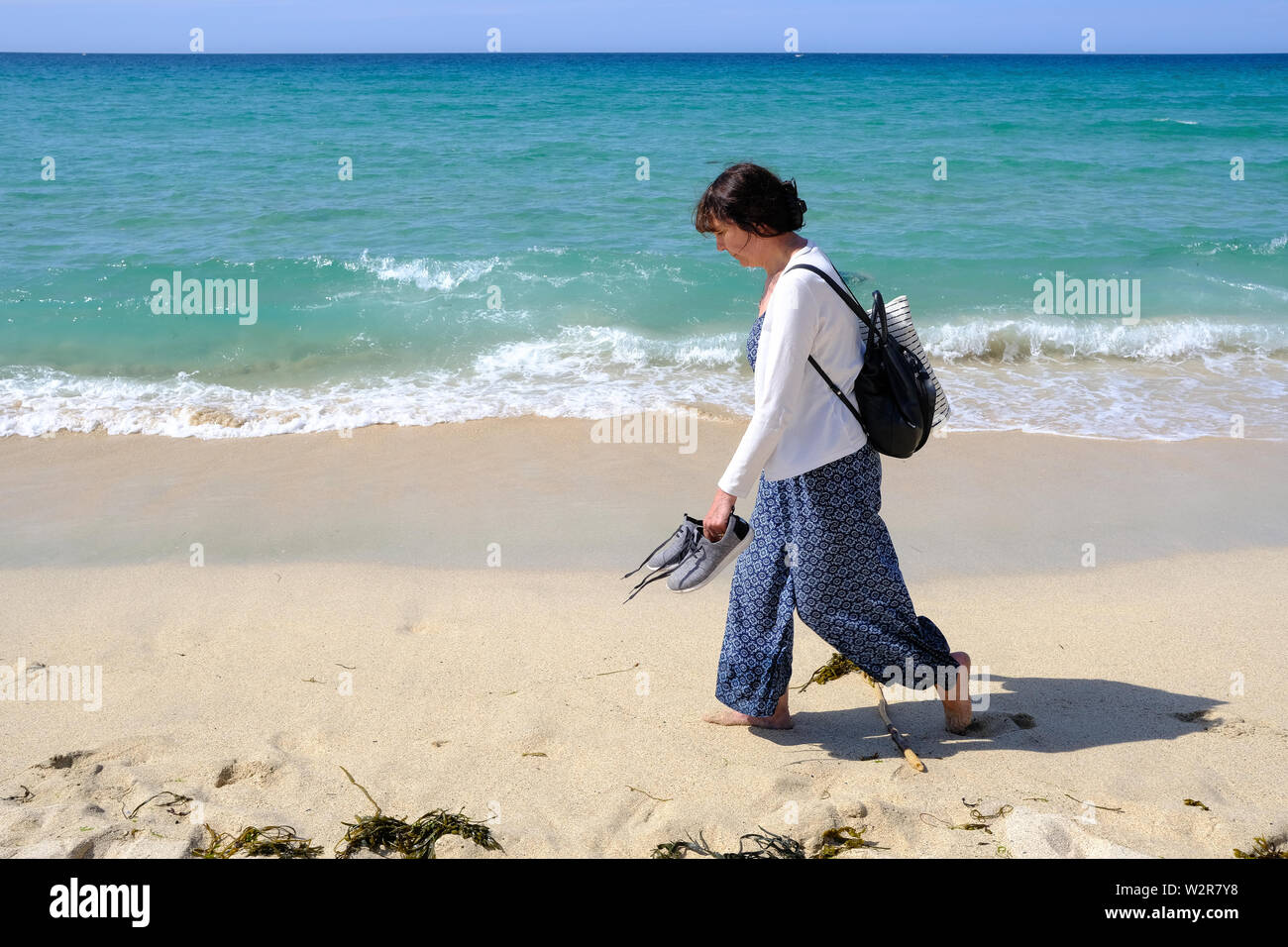 Eine Frau, die zu Fuß entlang der Küste an einem schönen Strand in St Ives in Cornwall. Stockfoto