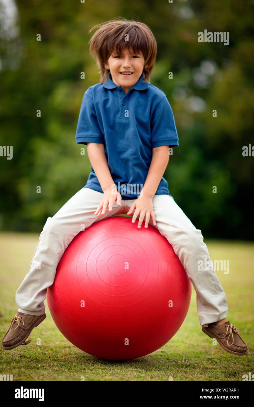 Junge Junge lächelt als er prallt auf einer schweizer Kugel. Stockfoto