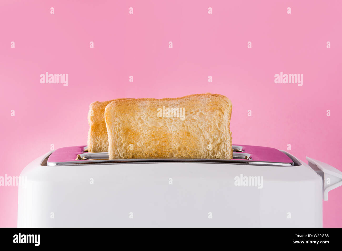 Getoastetes Toast Brot im Toaster weiß auf rosa Hintergrund Stockfoto