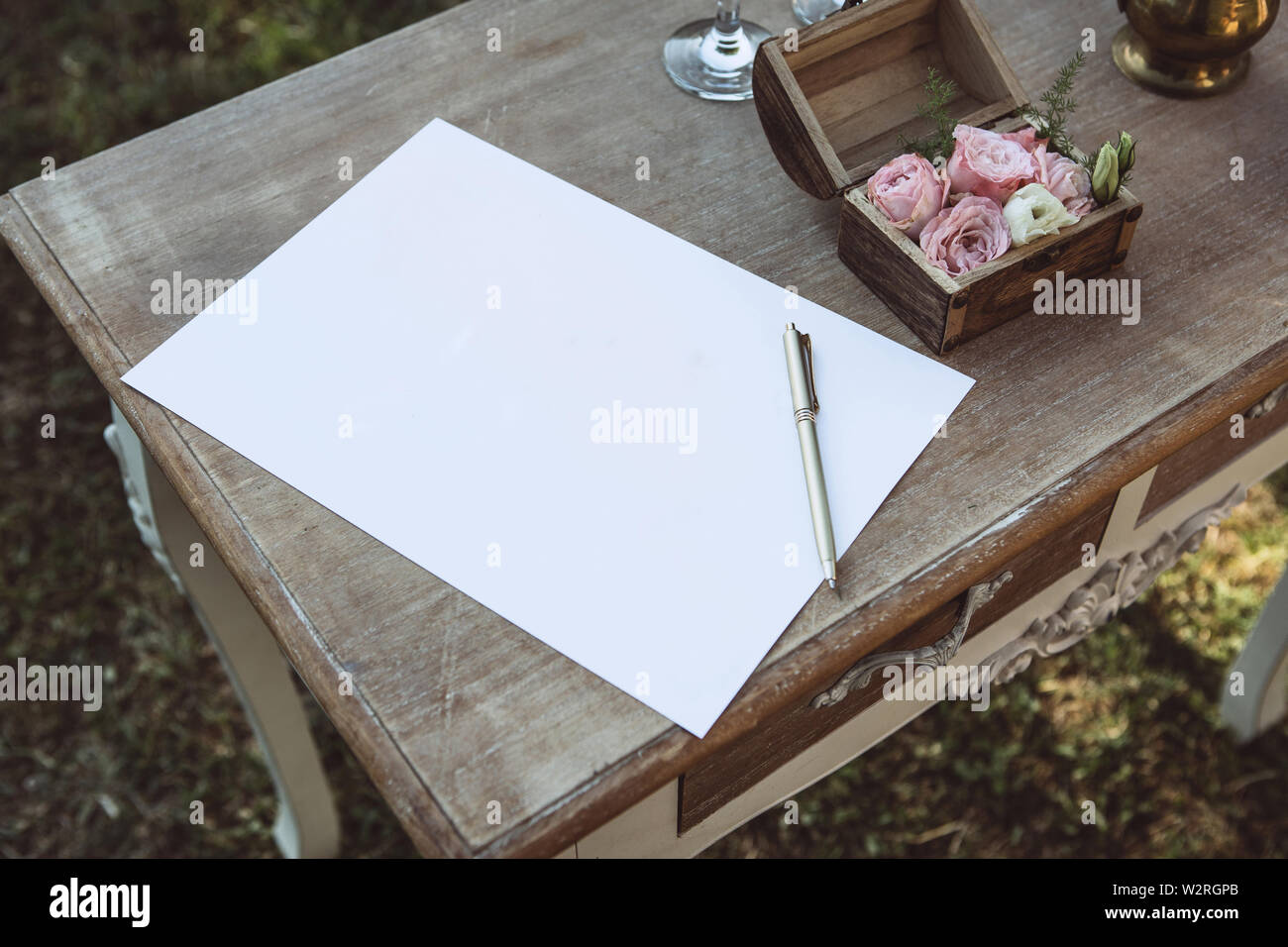 Ein leeres Blatt Papier und einen Stift auf einem hölzernen Tisch zum Schreiben einen Text oder ein Versprechen oder eine Hochzeit wünschen. Stockfoto