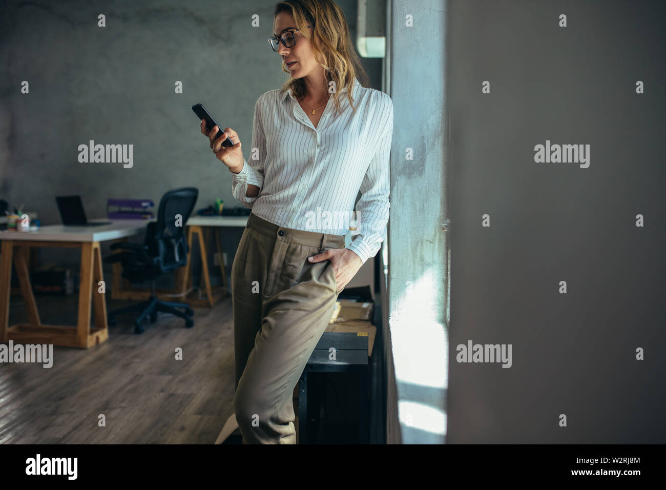 Geschäftsfrau, die sich in Büro- und mit Ihrem Smart Phone. Weibliche Unternehmer an Ihr Mobiltelefon suchen. Stockfoto