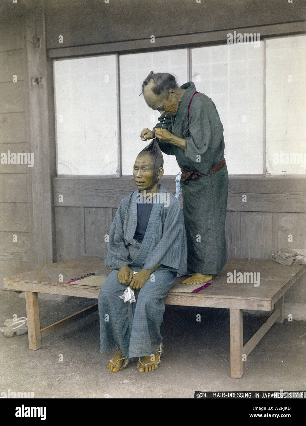 [1880s Japan - Japanische Friseur bei der Arbeit] - ein Friseur die Haare eines männlichen Kunden. Bis westlichen Frisuren während der Meiji Periode (1868-1912) gefördert wurden, japanische Männer trug ein chonmage Haarschopf. 19 Vintage albumen Foto. Stockfoto