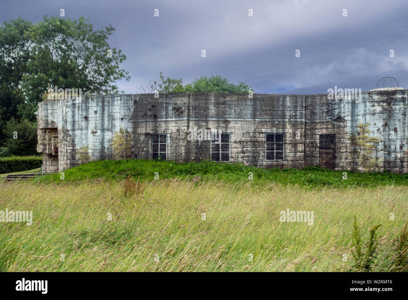 Tarnanstrich, zerstörten Gebäude auf der Rückseite des Gun casemate/Artillerie Bunker des Zweiten Weltkriegs Batterie d'Azeville Batterie, Normandie, Frankreich Stockfoto