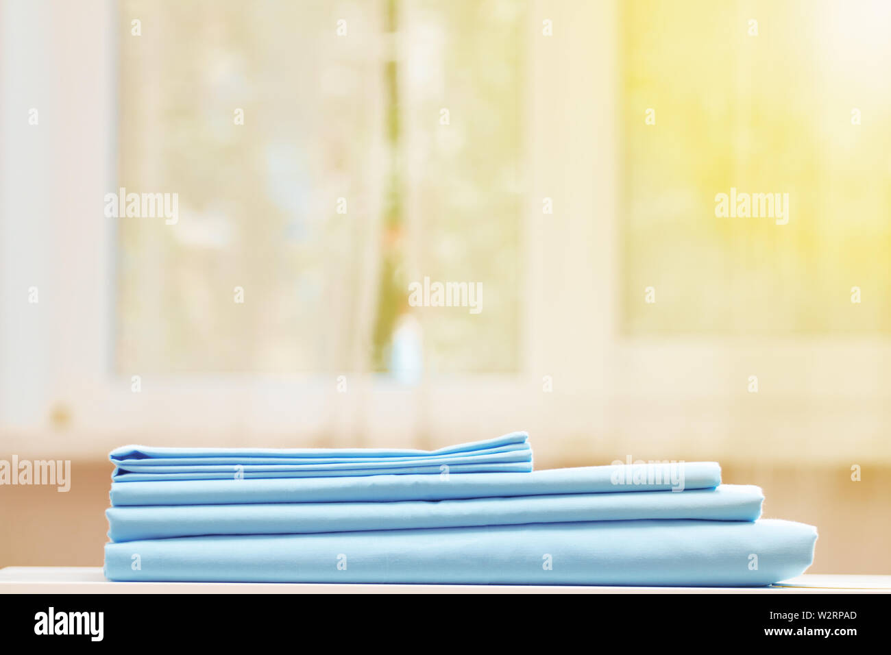 Closeup Stapel blau sauberes Bettzeug auf dem Tisch. Unscharfer Hintergrund. Fenster. Stockfoto