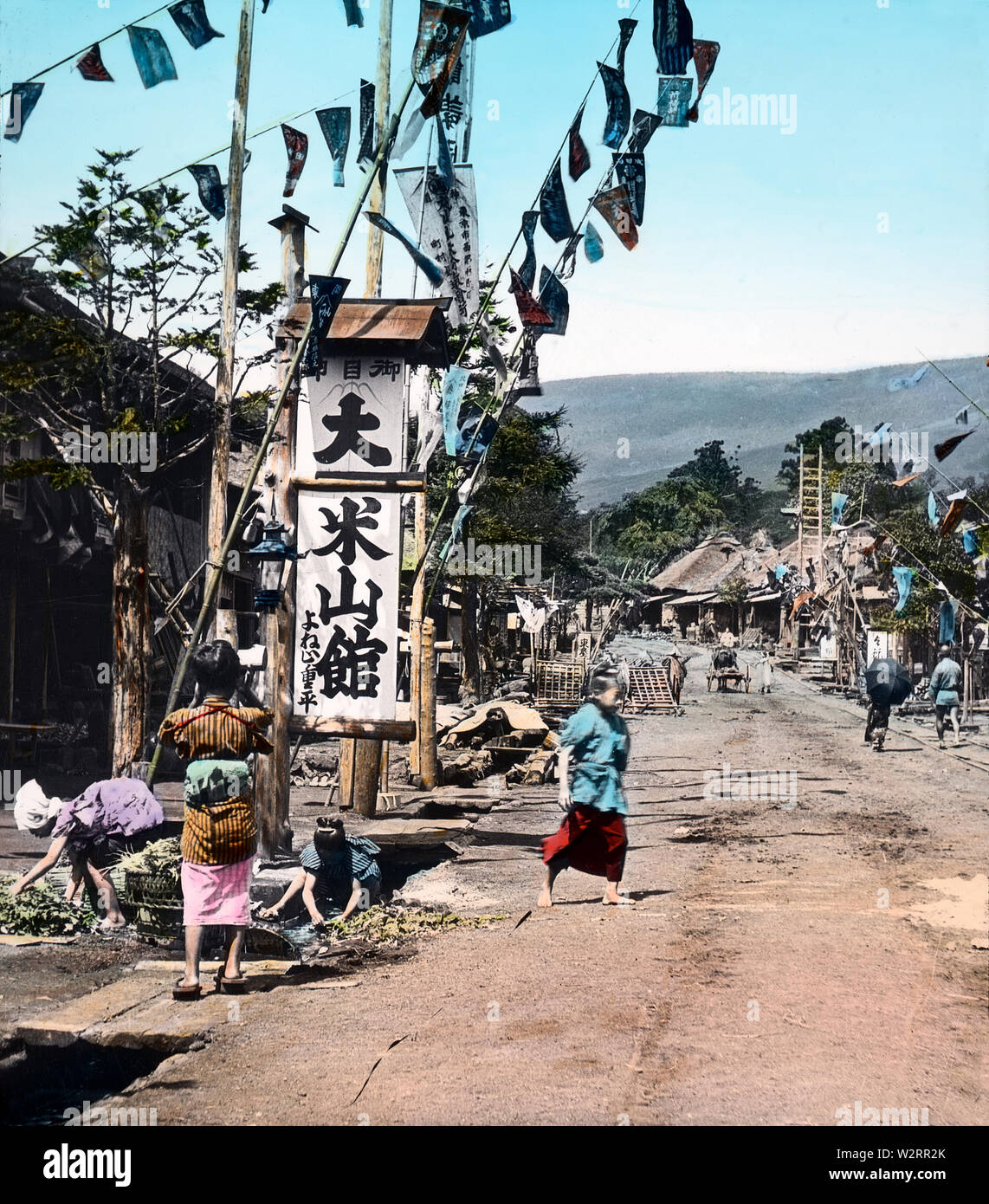 [1890s Japan - Japanische Dorf Scene] - Frauen sind das Waschen von Gemüse in einem Graben im Dorf Yoshida, auf dem Weg nach Mt. Fuji. Das Dorf sieht aus wie ein typischer post Stadt. 19 Vintage Glas schieben. Stockfoto