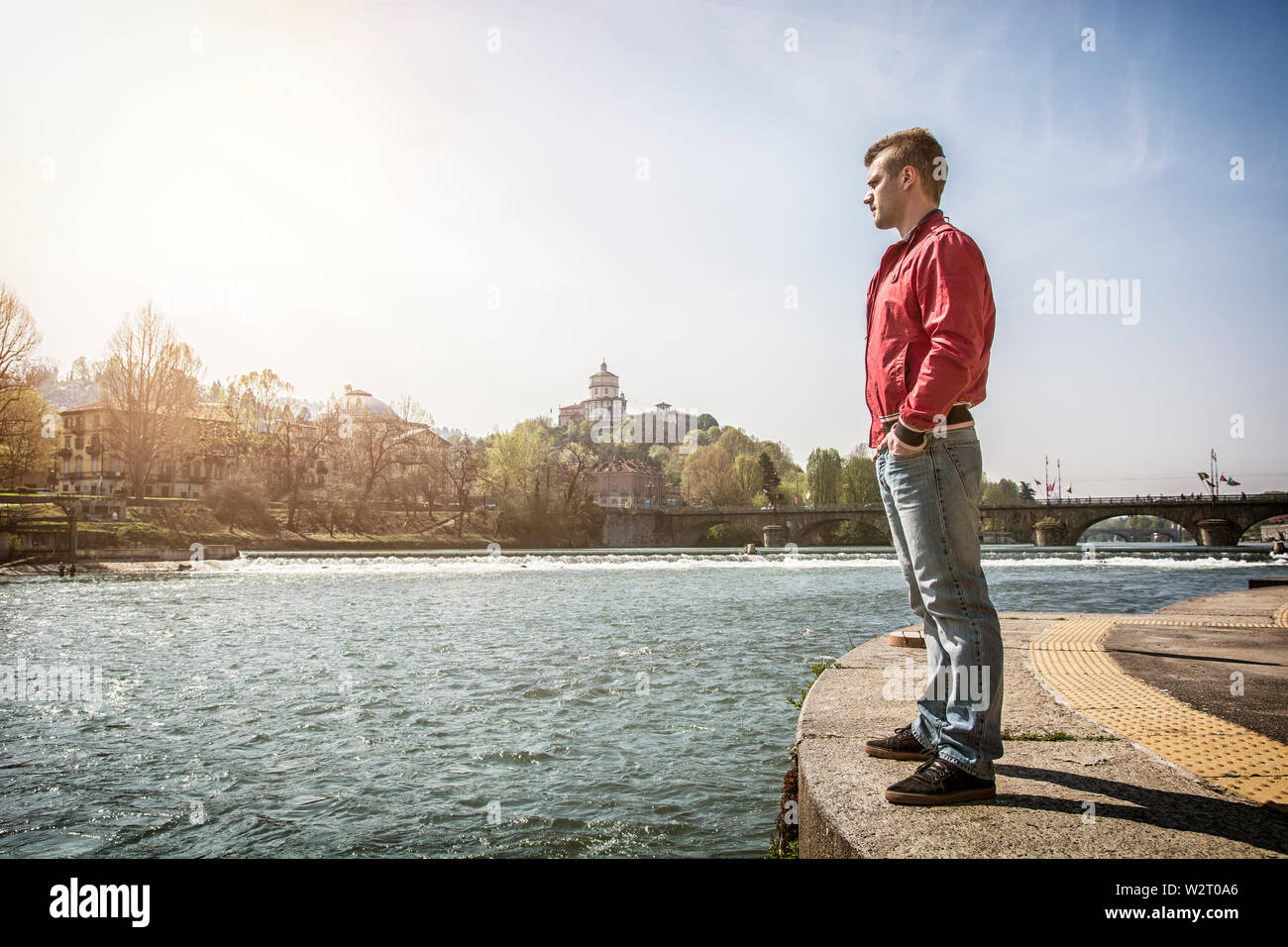 Nachdenklicher junger Mann, der am Fluss in Turin sitzt Stockfoto