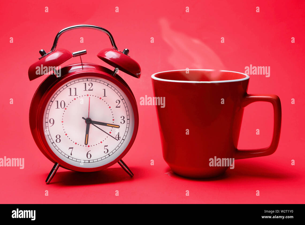 Kaffee mit Dampf und und Wecker für immer bereit für neue tägliche Aktivität. Stockfoto