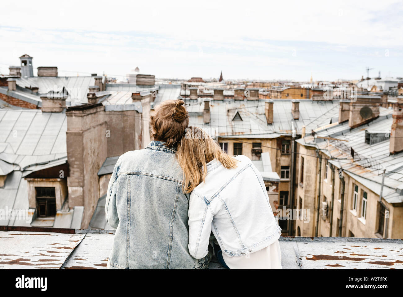 Ein junges Paar sitzt auf dem Dach bewundert und einer schönen Aussicht auf die Stadt. Romantik, Liebe und vertrauensvolle Beziehungen. Oder er Traum oder digital detox zusammen. Stockfoto