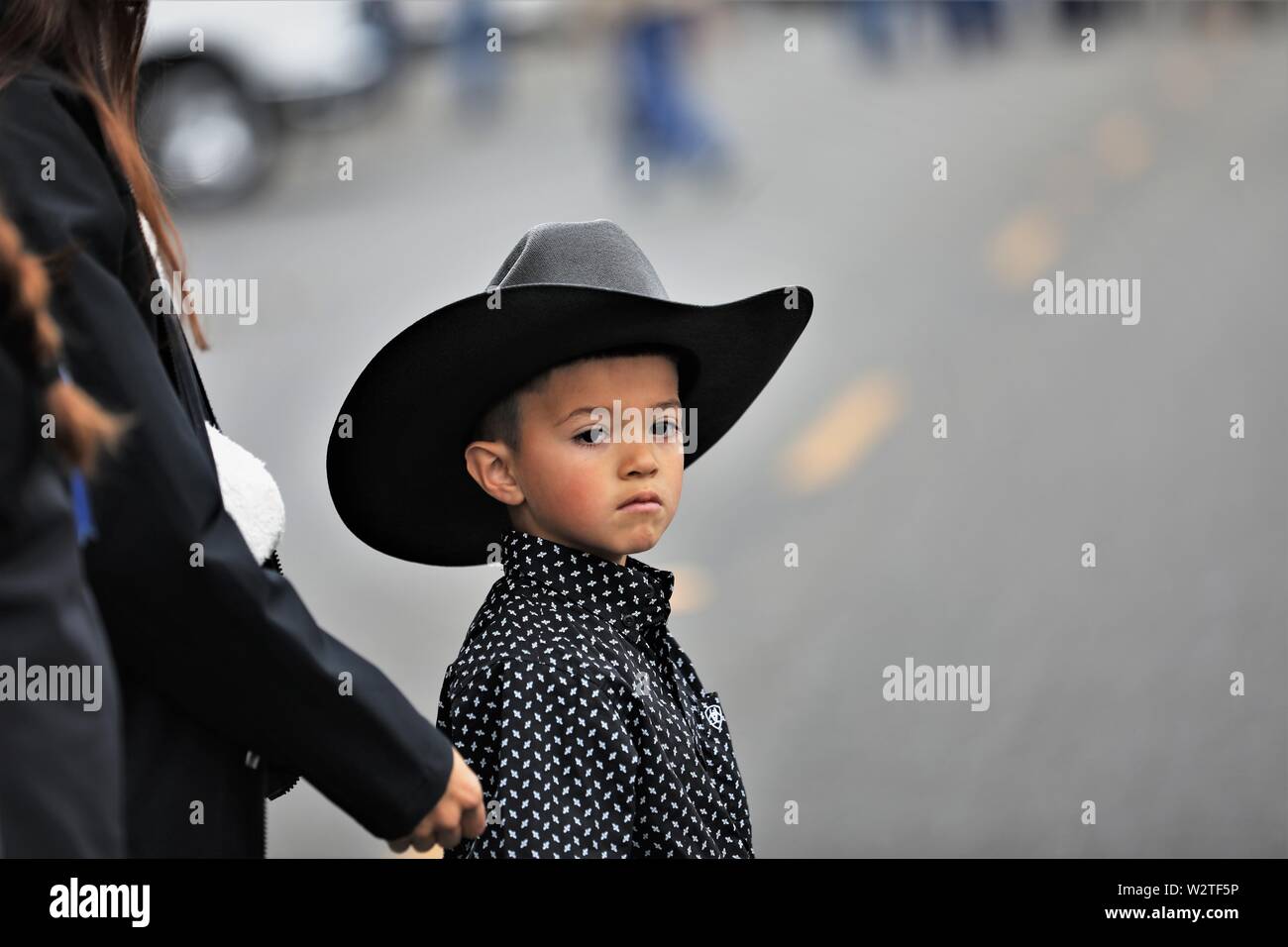 Junger hispanischer Junge mit schwarzem Hut bei einer öffentlichen Parade, die ihre mexikanische Ranchhaltung und Cowboy- und Cowgirl-Tradition in Kalifornien feiert Stockfoto