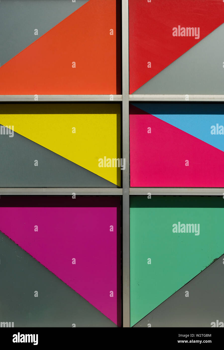 Farbenfrohe abgewinkelten Formen in Windows auf der Seite eines Gebäudes Stockfoto